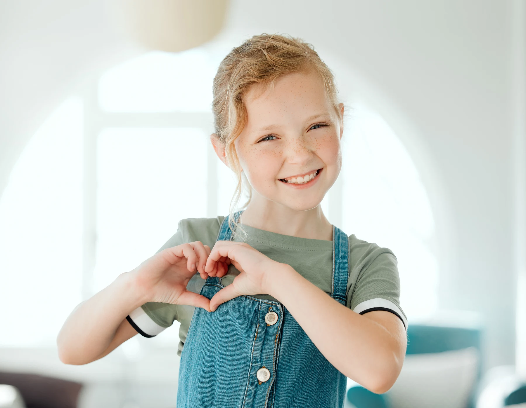 Smiling child making a heart shape with her hands
